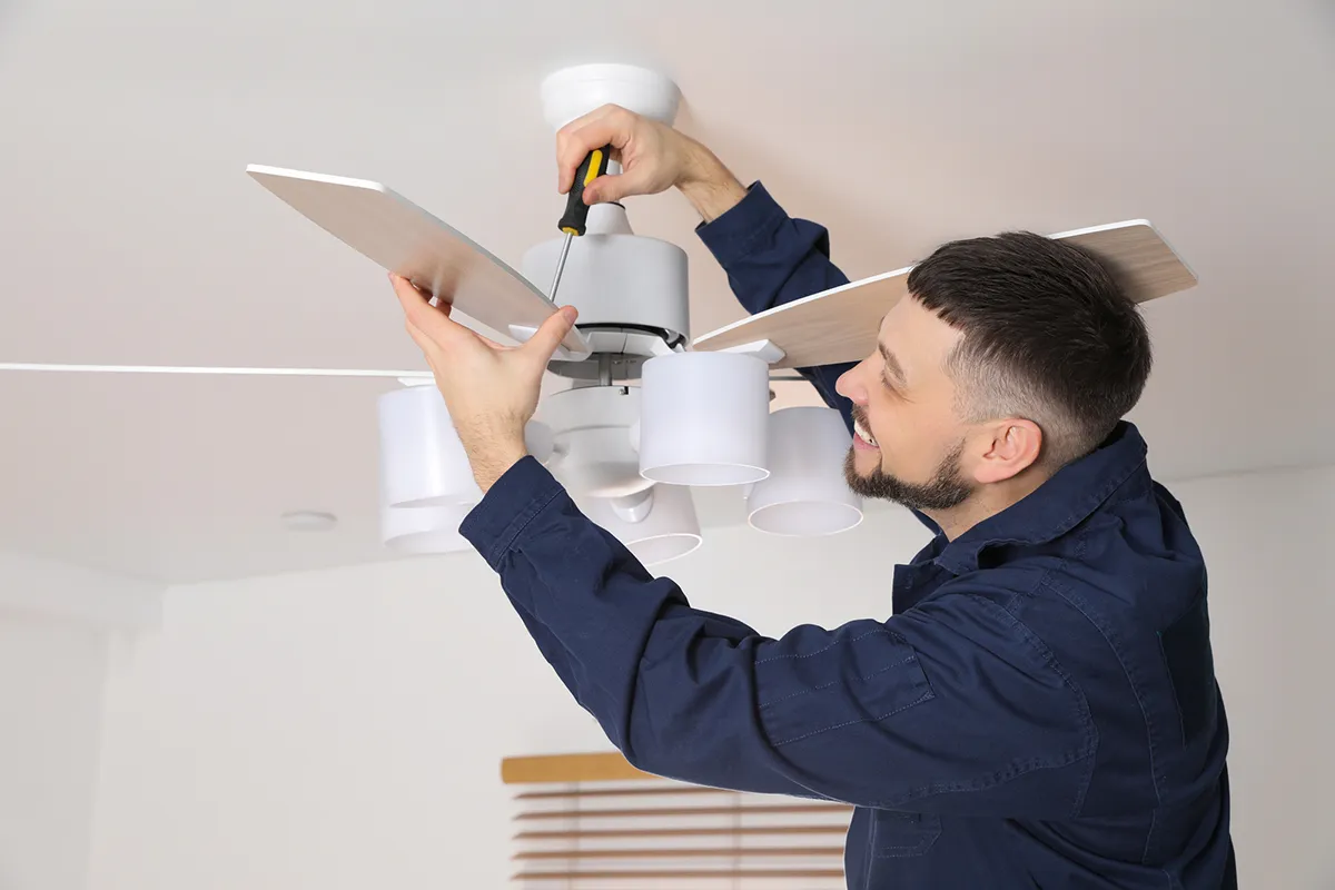 Electrician installing a ceiling fan with light fitting