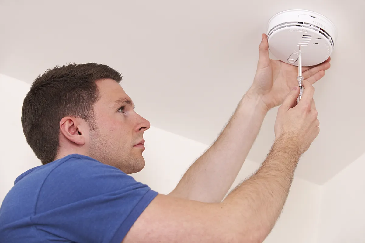 Electrician installing a smoke detector on a residential ceiling